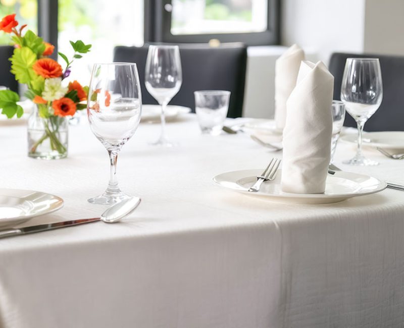 elegant table setting with crisp white linens sparkling glassware and a vibrant floral centerpiece. the soft natural light enhances the mood of sophistication and tranquility creating an inviting atmosphere for a special occasion.